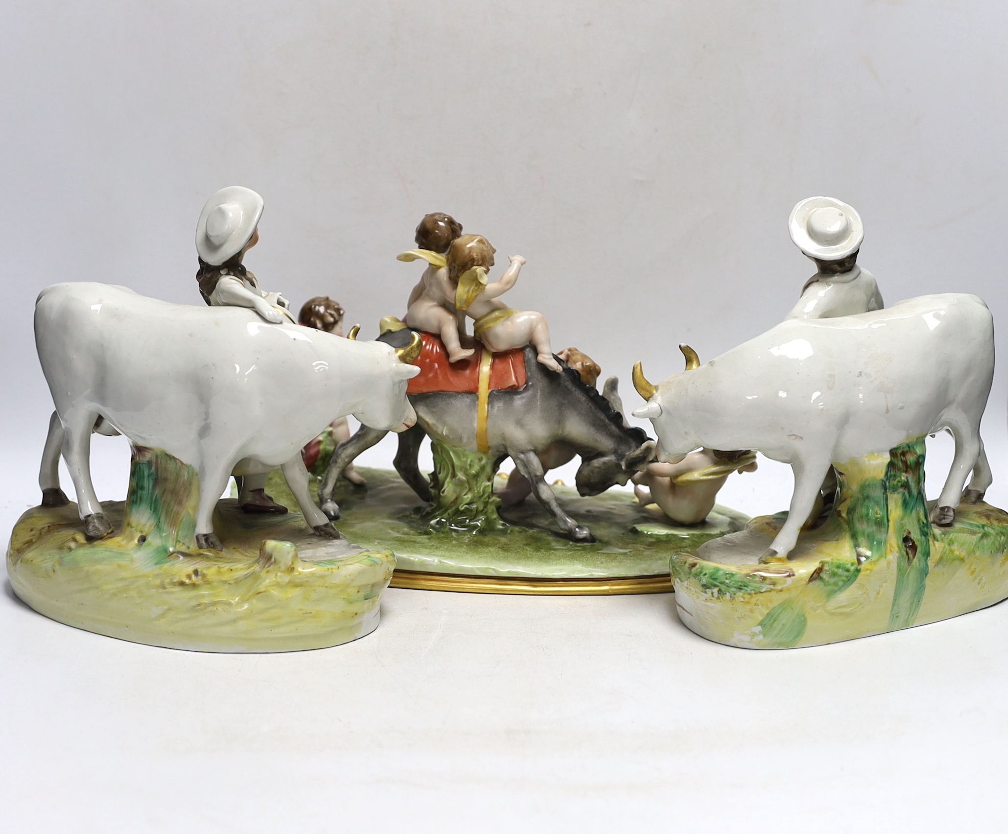 A pair of 19th century Staffordshire cow groups and an Italian donkey and cherub group, tallest 20.5cm